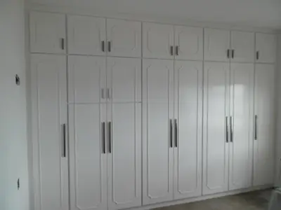 Closet planejado: armários brancos do piso ao teto