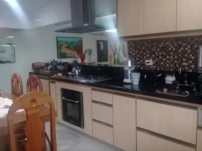 Cozinha planejada: armários em tom claro, cooktop e bancada em granito preto