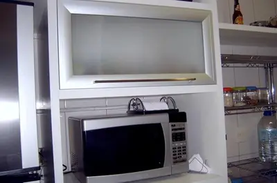 Cozinha planejada: nicho para micro-ondas e armário com porta de vidro
