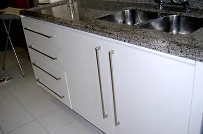 Cozinha planejada: balcão branco com puxadores em aço