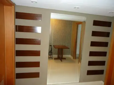 Sala planejada: painel em madeira com detalhes ripados no hall